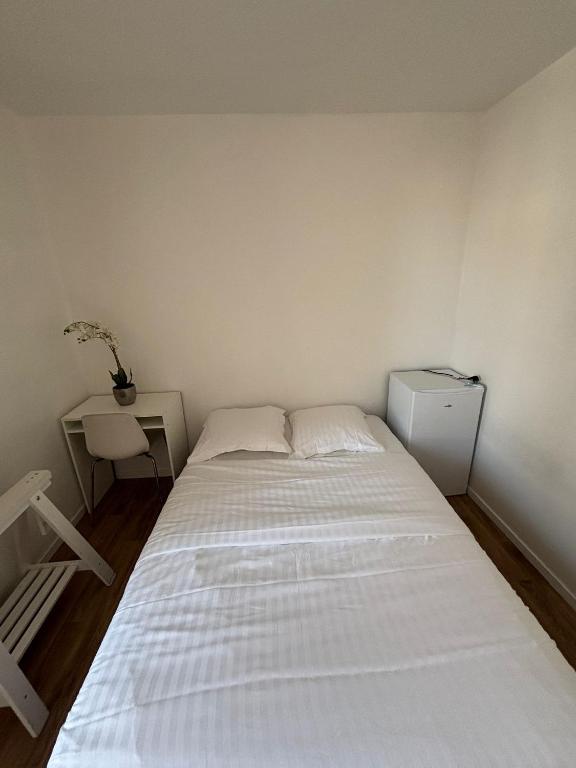 ein Schlafzimmer mit einem großen weißen Bett und einem Schreibtisch in der Unterkunft Chambre à 20 minutes de Paris NOTRE DAME, APPARTEMENT COMMUN in Épinay-sur-Seine