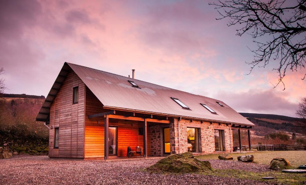 Cabaña de madera con techo de metal y ventanas en The Steading, en Aberfeldy