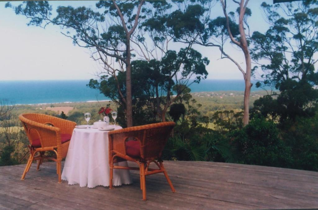 a table and chairs on a deck with a view of the ocean at Sacred Mountain Retreat in Nambucca Heads