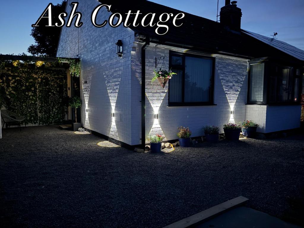 a white building with a sign that reads ash cottage at Ash Cottage in Tollerton