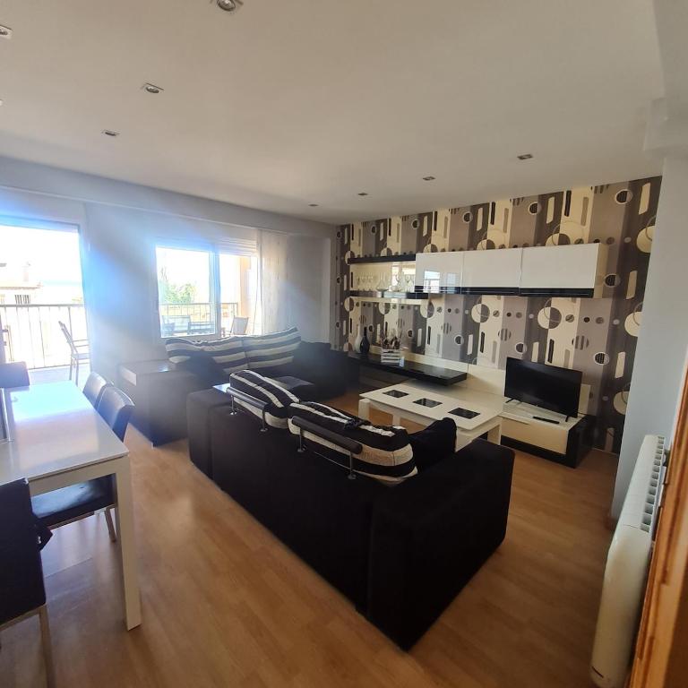 a living room with couches and a table and a television at Nules Beach Apartment in Moncófar