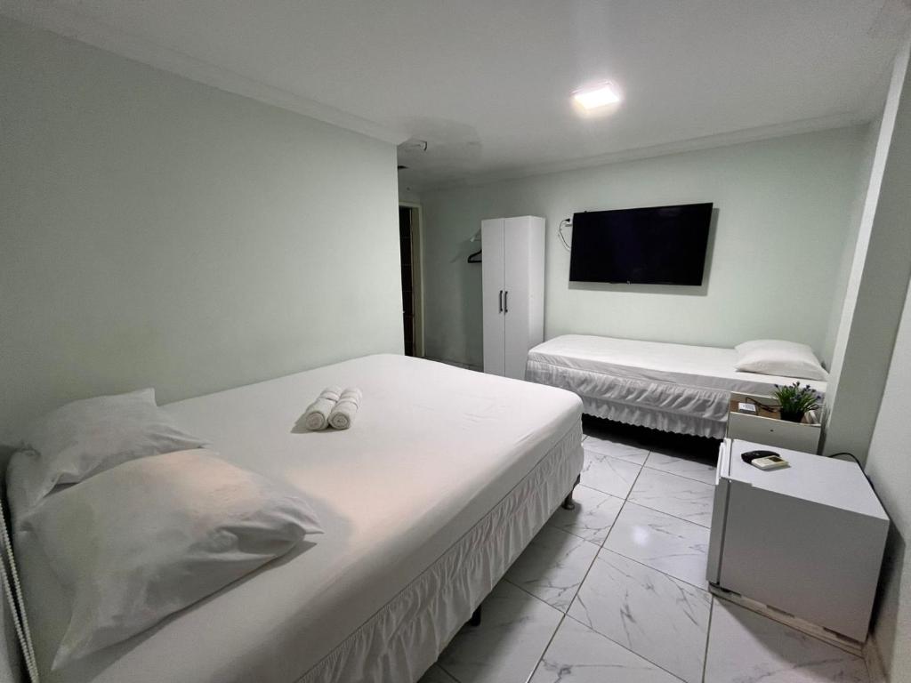 a bedroom with two beds and a flat screen tv at Pousada Alameda Boa Vista in Recife