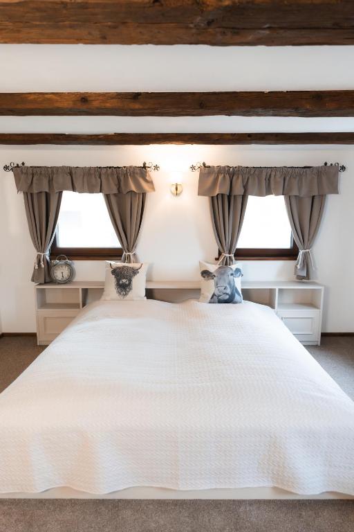 a bedroom with a white bed with two windows at Ferienunterkunft Heimatfleckerl in Geisenhausen