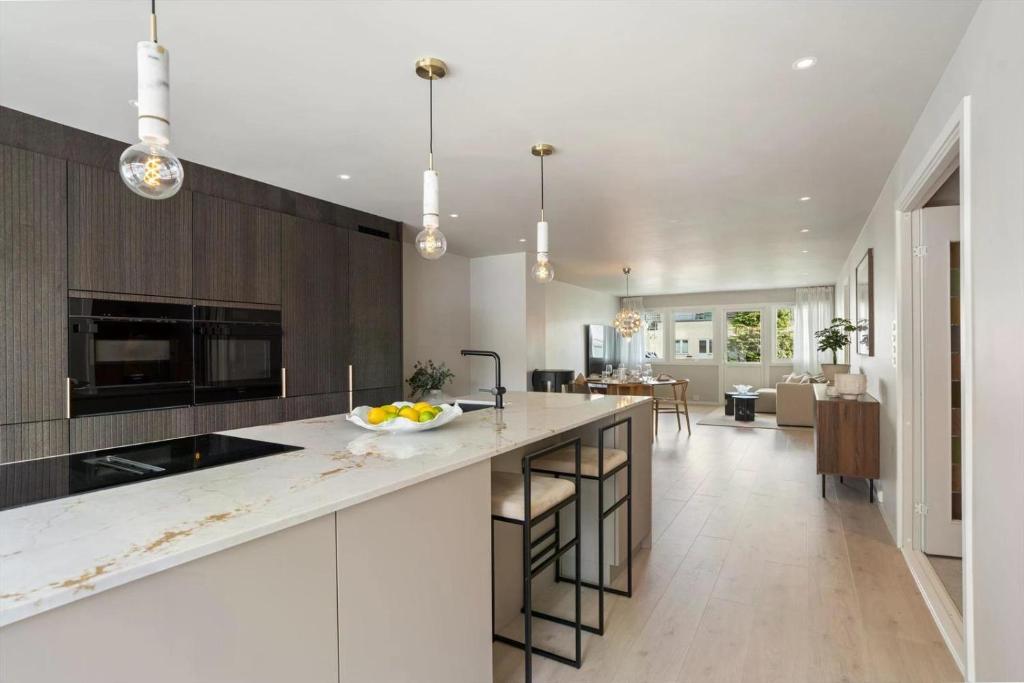 una cucina con piano di lavoro bianco e un soggiorno di Newly renovated exclusive big apartment, city center, 3 bedrooms, 2 bathrooms with WC and more a Kristiansand