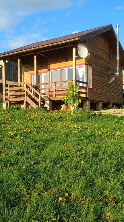 a log house with a porch and a grass field at Casuta de Vacanta Marisel, Cluj in Mărişel