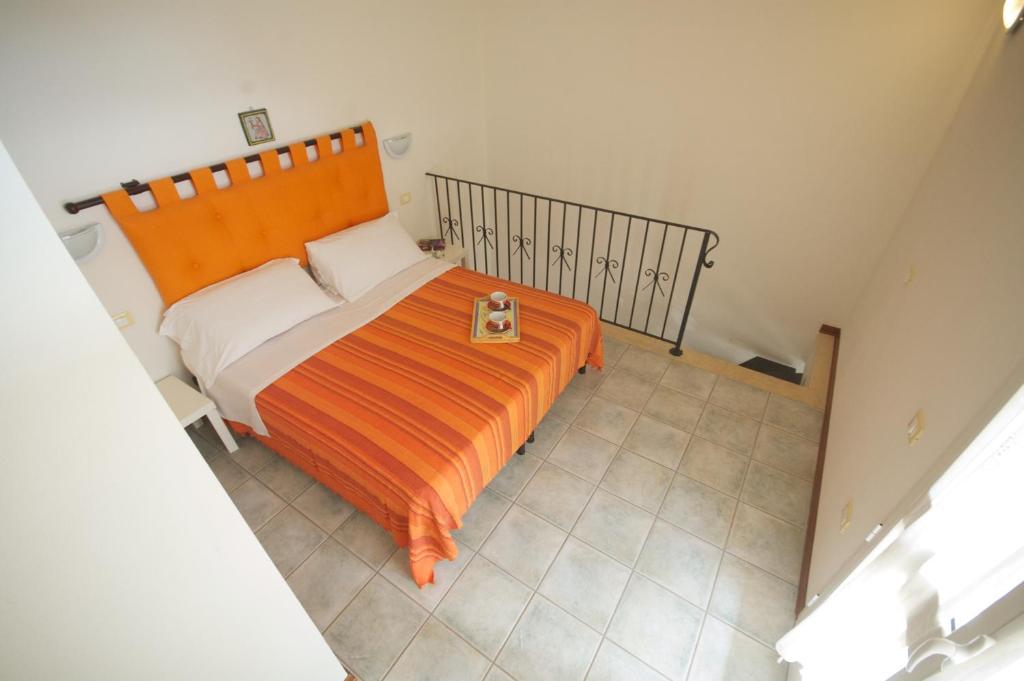 1 dormitorio con 1 cama con colcha de color naranja en Residence Loggetta Margherita, en San Vincenzo