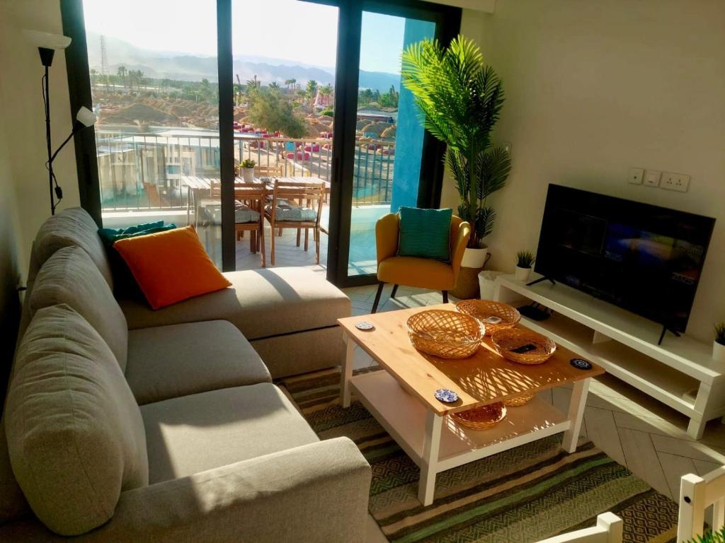 a living room with a couch and a tv and a table at Cozy Apartment with Private Beach, couples and families only in Aqaba