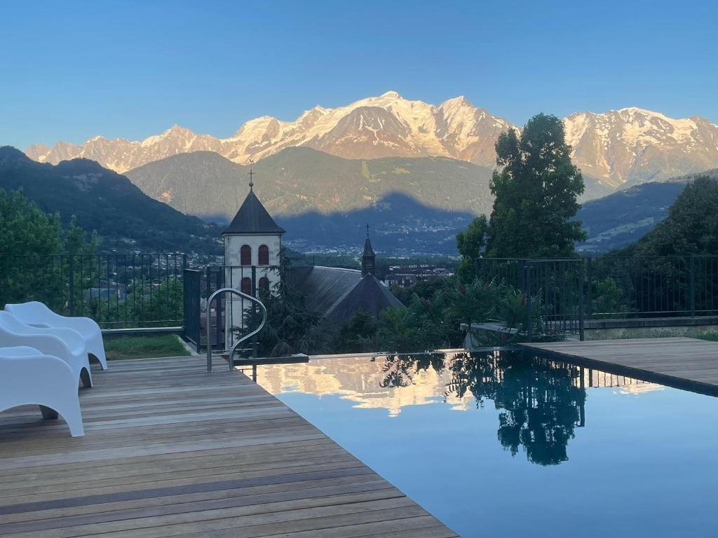un complexe avec une piscine, une église et des montagnes dans l'établissement Tour médiévale rénovée au cœur du Pays du Mont-Blanc, à Sallanches