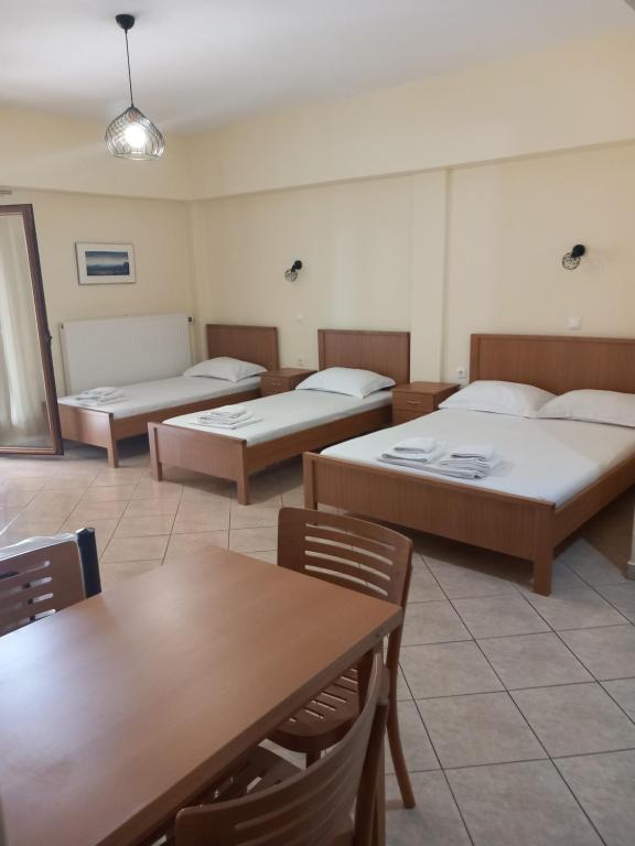a room with four beds and a table and chairs at efihouse in Nea Vrasna