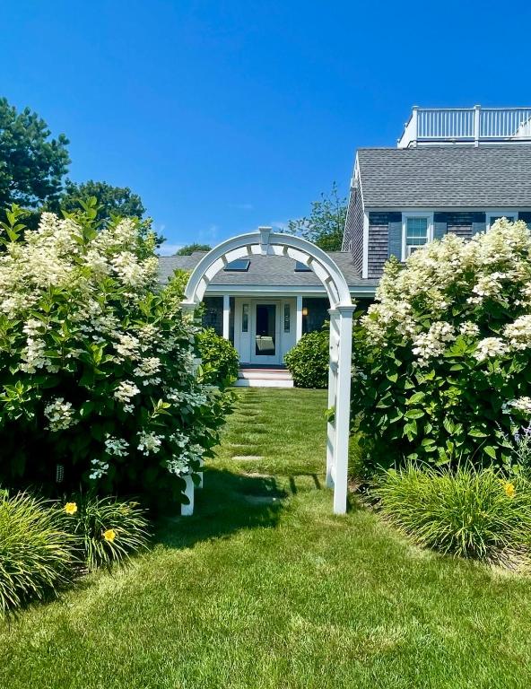 a garden with a white arch in front of a house at Katama Family Fun in Edgartown