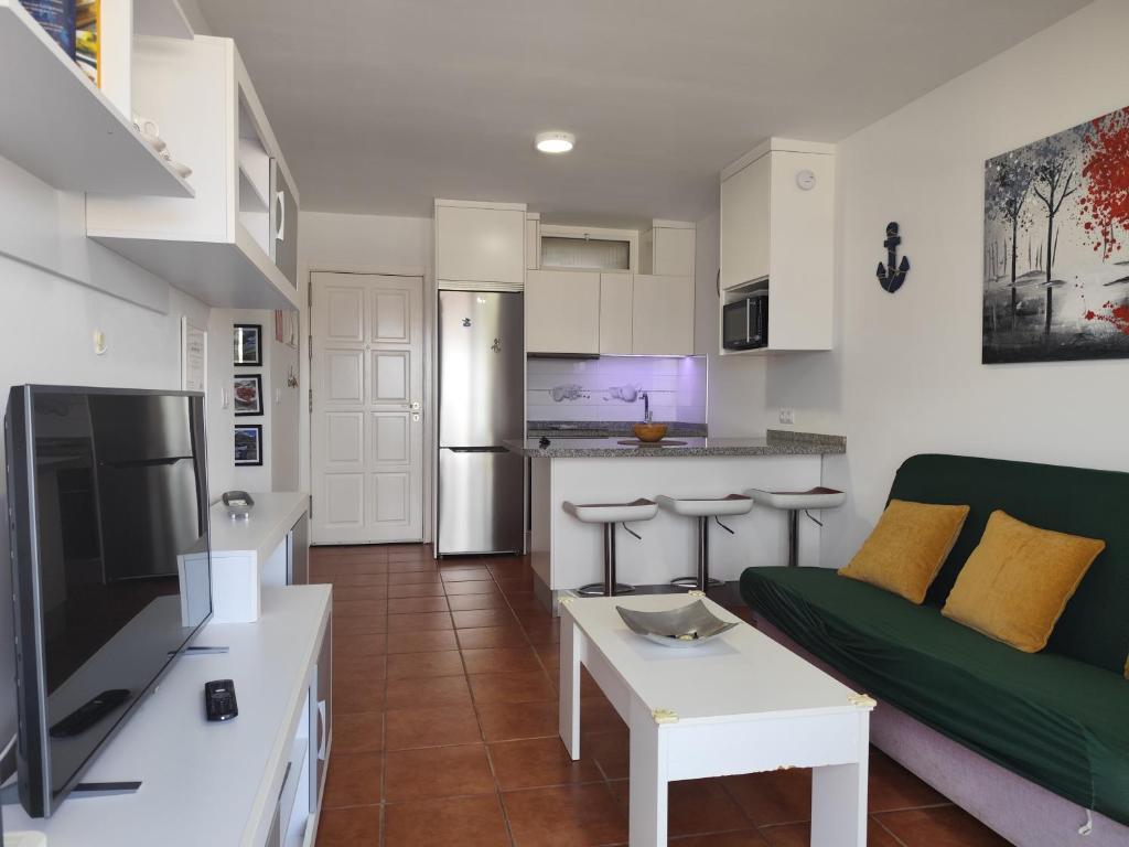a living room with a green couch and a kitchen at Horizon Views - Excellent location with ocean view in Puerto Rico de Gran Canaria