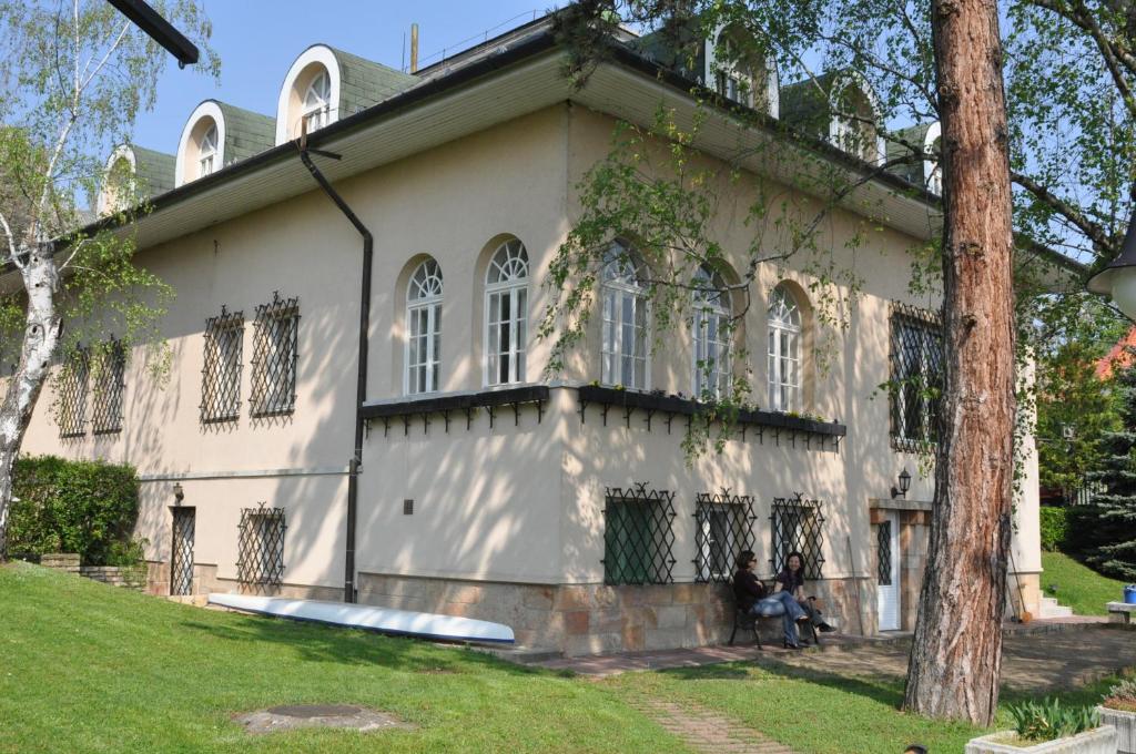 una casa con dos personas sentadas frente a ella en Villa Székely en Leányfalu