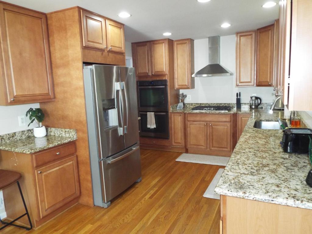 a kitchen with wooden cabinets and a stainless steel refrigerator at 9 Bedroom 6 Bath - Entire House in Alexandria