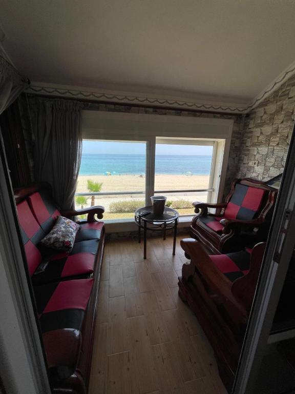 a living room with two chairs and a table and a window at BEACHFRONT VUE SUR MER APPARt in Dar Merah Deriba