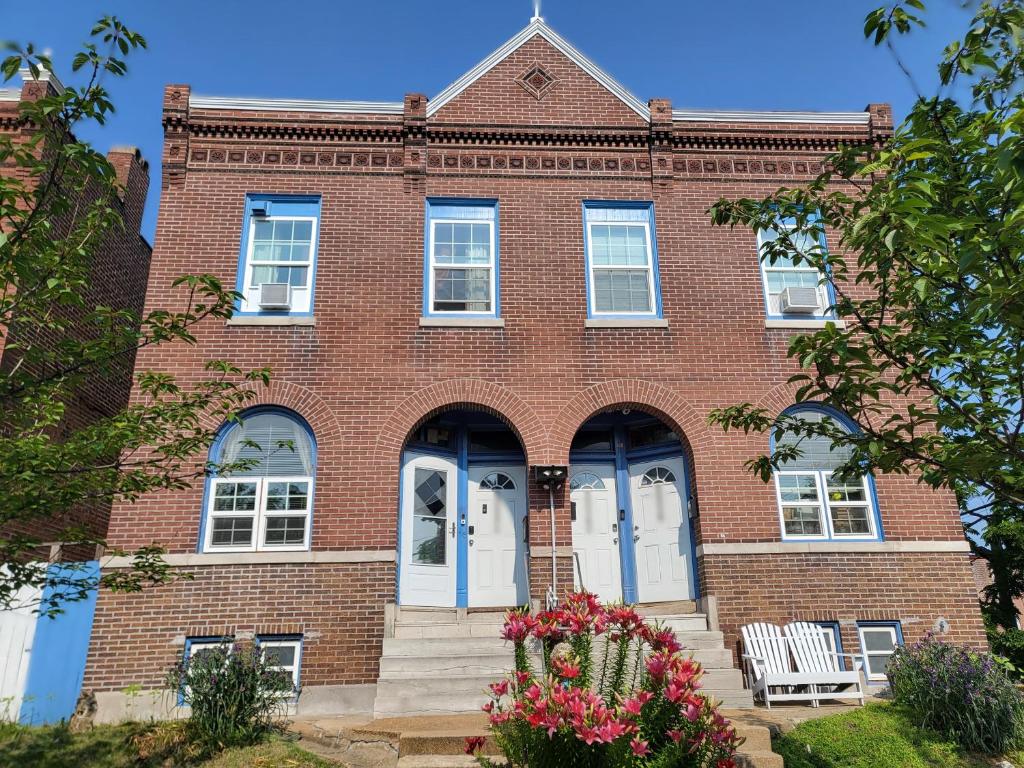 a red brick building with white doors and flowers at The Bleu Guitar Suite in Saint Louis