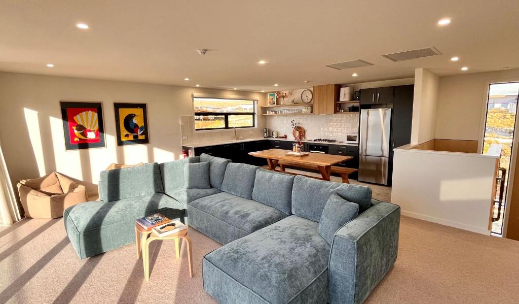 a living room with a blue couch and a kitchen at Rabbiters Run - Lake Tekapo in Lake Tekapo