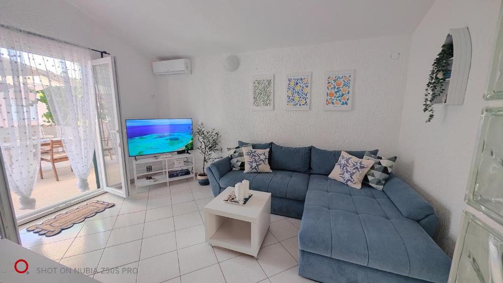 a living room with a blue couch and a tv at Apartman Lunna in Vrsi