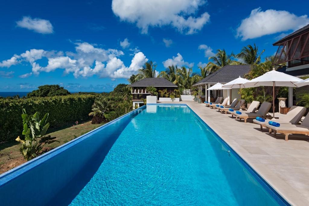 una piscina infinita con sillas y sombrillas junto a una villa en Tom Tom by Blue Sky Luxury, en Saint James