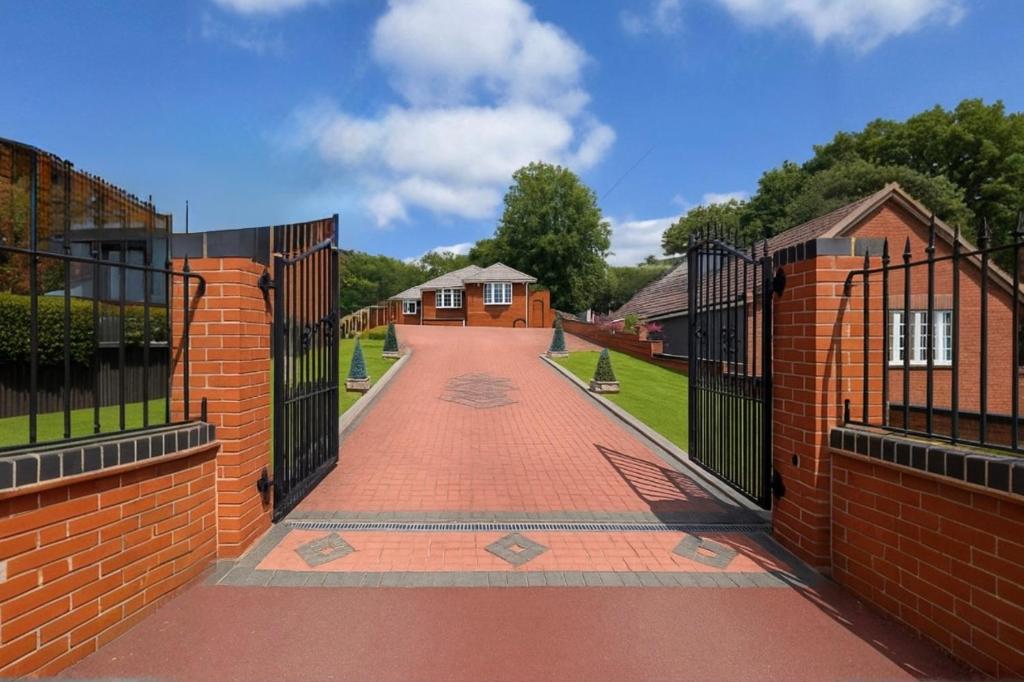 a brick fence with a brick walkway between two houses at Stylish Detached Bungalow in Dudley
