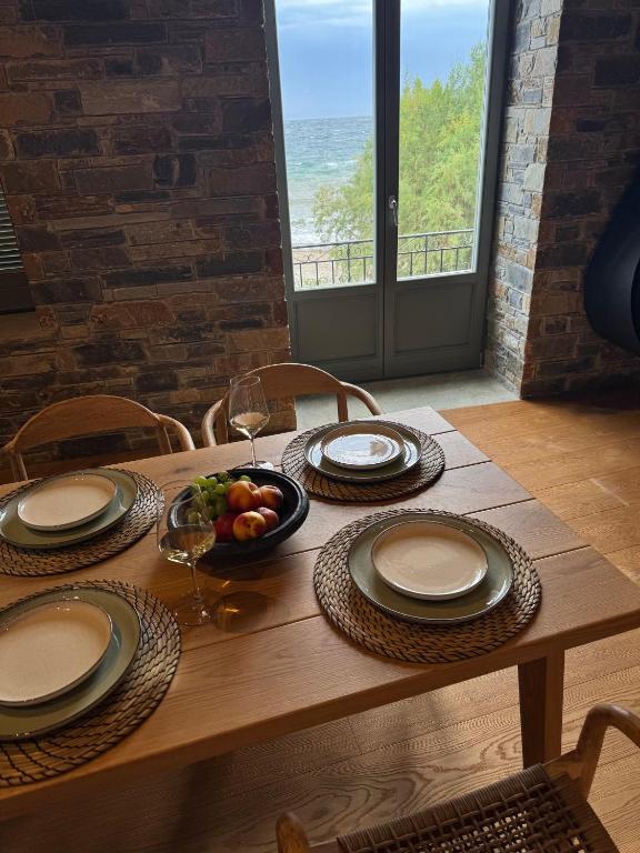 a wooden table with plates and a bowl of fruit at EJ Boutique Suites in Milina