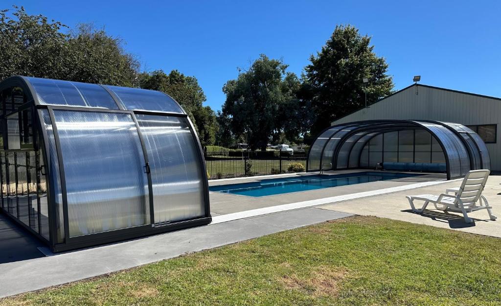 a large metal building with a swimming pool next to a house at Otorohanga Kiwi Holiday Park in Otorohanga