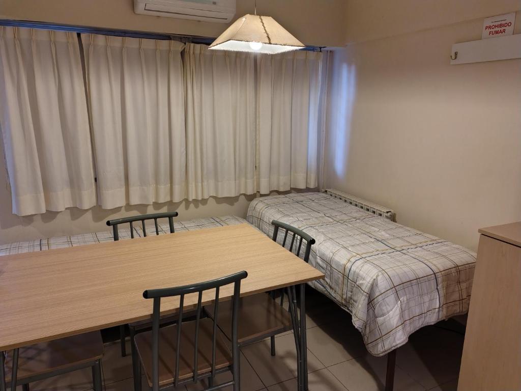 a room with two beds and a table and chairs at Departamentos Pórtico Sur, monoambientes con cochera in Cipolletti