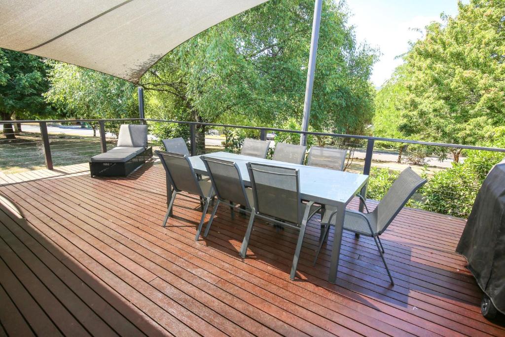 een houten terras met een tafel en stoelen erop bij Mystic Mountain Lodge in Bright