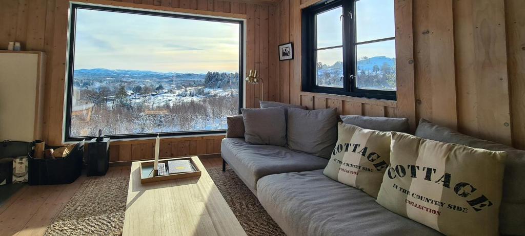 een woonkamer met een bank en een groot raam bij Panoramic Cabin With Forest And Mountain Views in Sveio