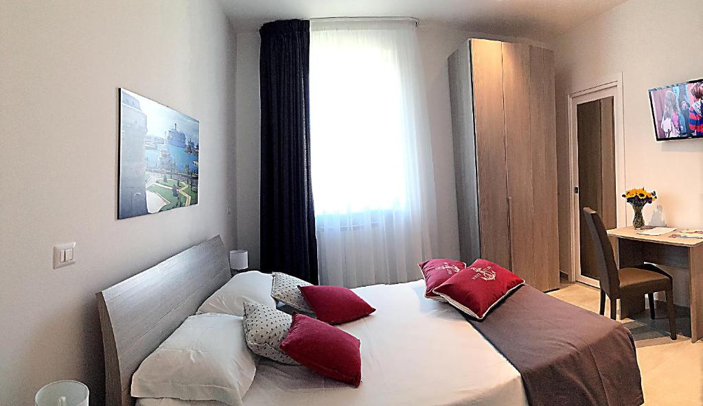Un dormitorio con una cama con almohadas rojas. en Quattro Stelle al Porto Guest House, en Civitavecchia