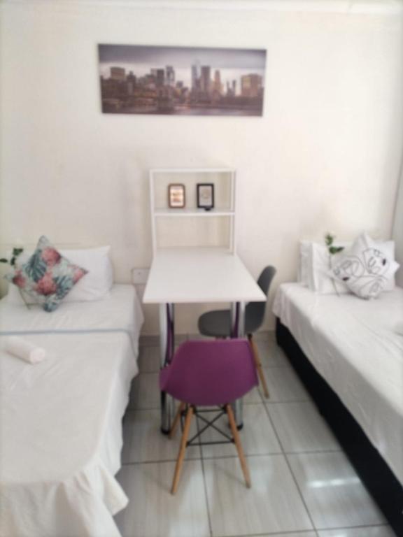 帕拉博鲁瓦C-Rane Lodge 2的有两张床、一张桌子和一把椅子的房间