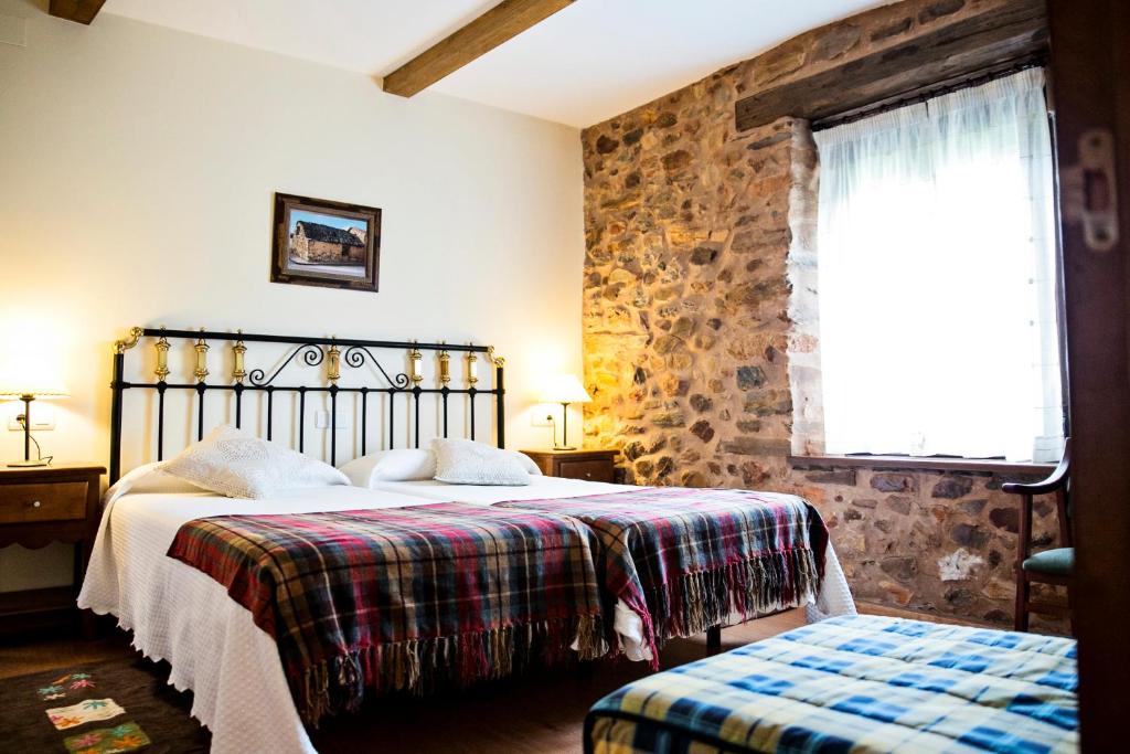 1 dormitorio con cama y pared de piedra en Hotel Rural El Habanero, en Destriana