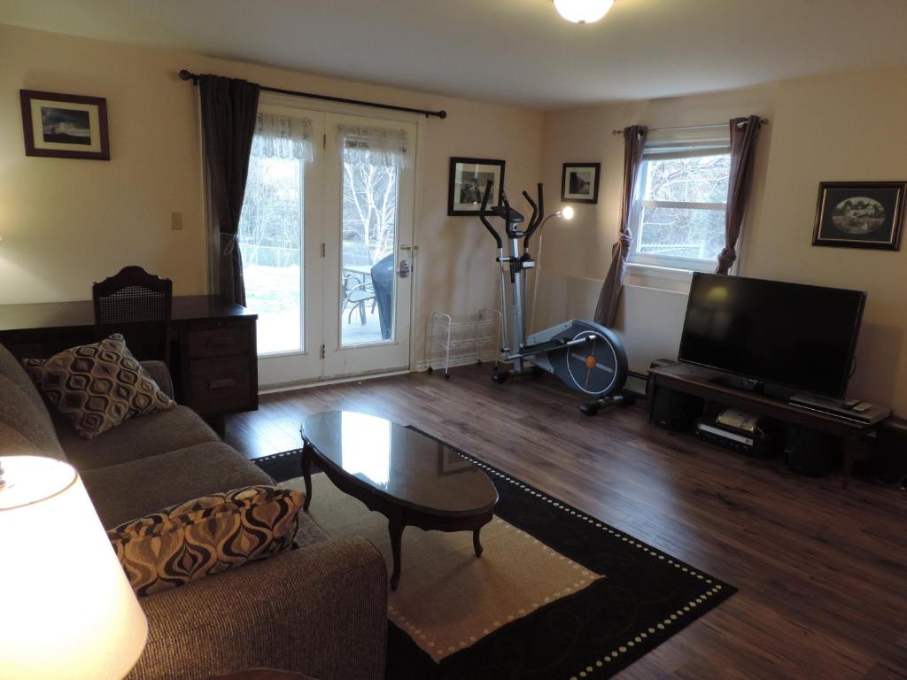 uma sala de estar com um sofá, uma mesa e uma televisão em Wright's Creek Apartment em Charlottetown