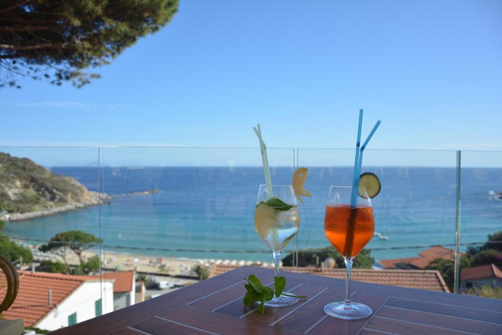 two glasses on a table with a view of the ocean at Hotel Baia Imperiale in Campo nell'Elba