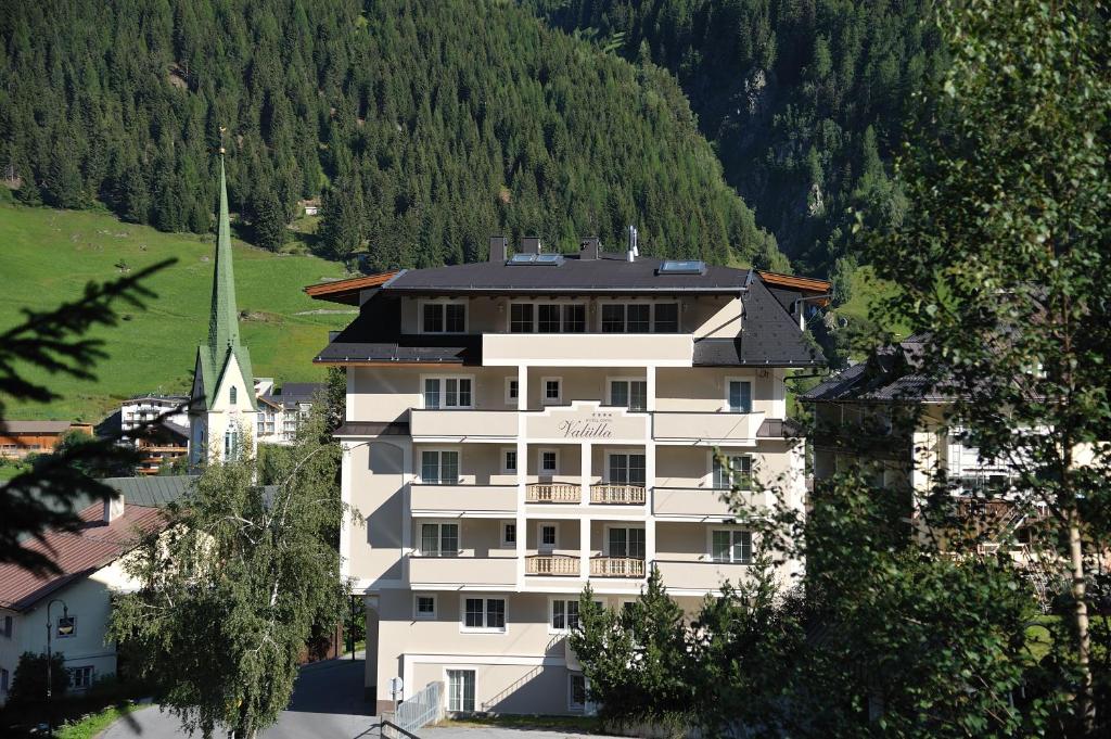 a large white building in front of a church at Hotel Garni Valülla in Ischgl