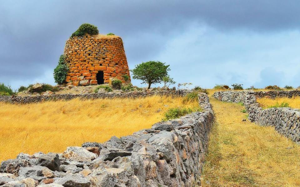 a stone wall and a building on a field at Agriturismo Le Mimose in Arborea