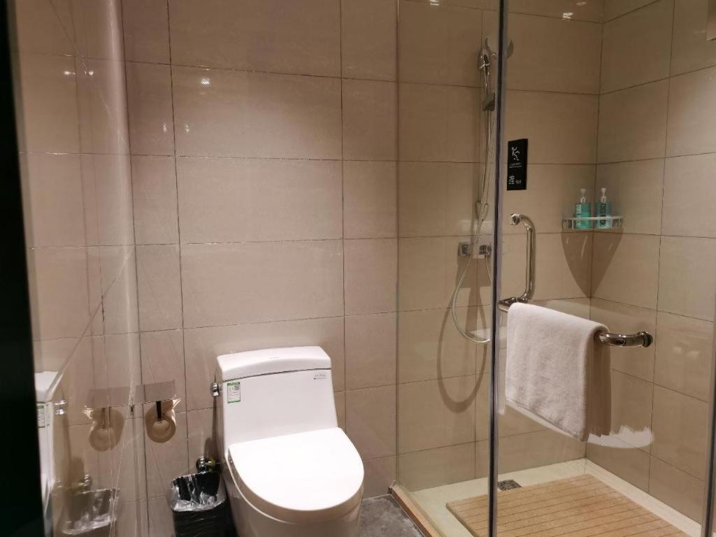 a bathroom with a toilet and a shower with a glass door at City Comfort Inn Qianjiang Government in Qianjiang