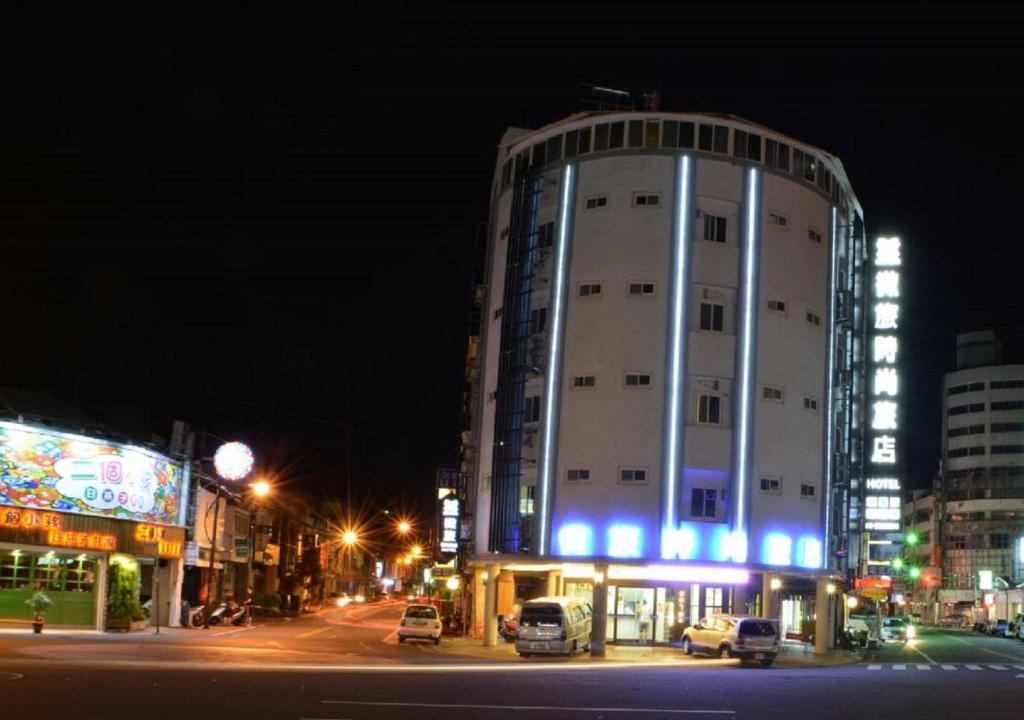 斗六的住宿－微旅時尚旅店，一座白色的大建筑,晚上在城市里亮着蓝色的灯光