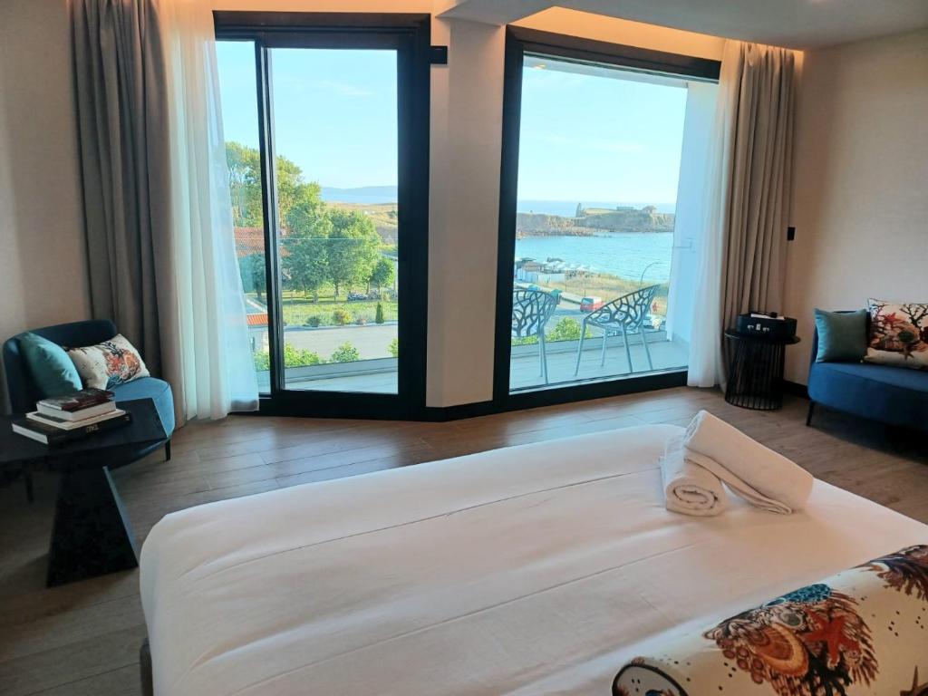 Un dormitorio con una cama grande y grandes ventanales. en Hotel Delfin Azul, en A Lanzada