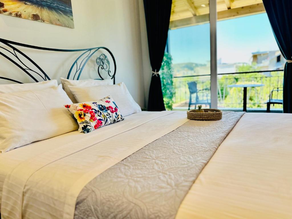 ein Schlafzimmer mit einem Bett mit einem großen Fenster in der Unterkunft Simadhes Garden Rooms in Himarë
