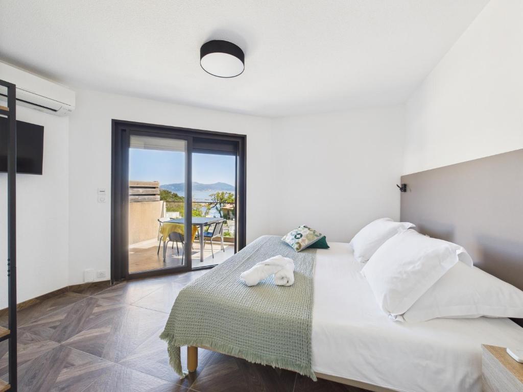 a white bedroom with a bed and a balcony at Résidence Aigue Marine in Coti-Chiavari