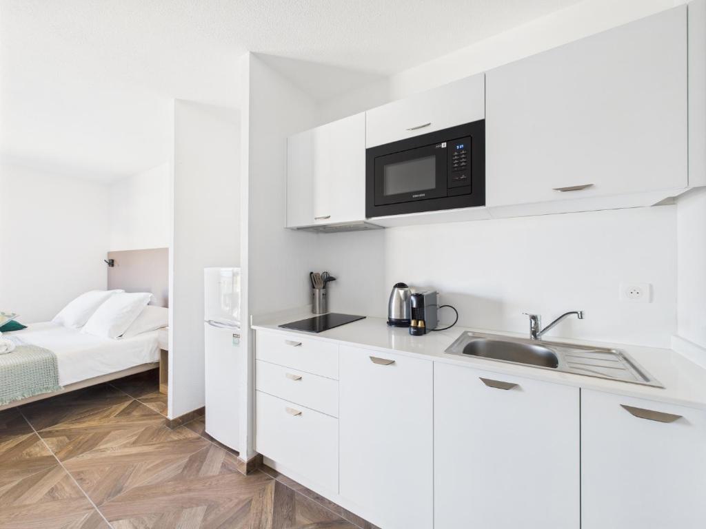 a white kitchen with a sink and a microwave at Résidence Aigue Marine in Coti-Chiavari