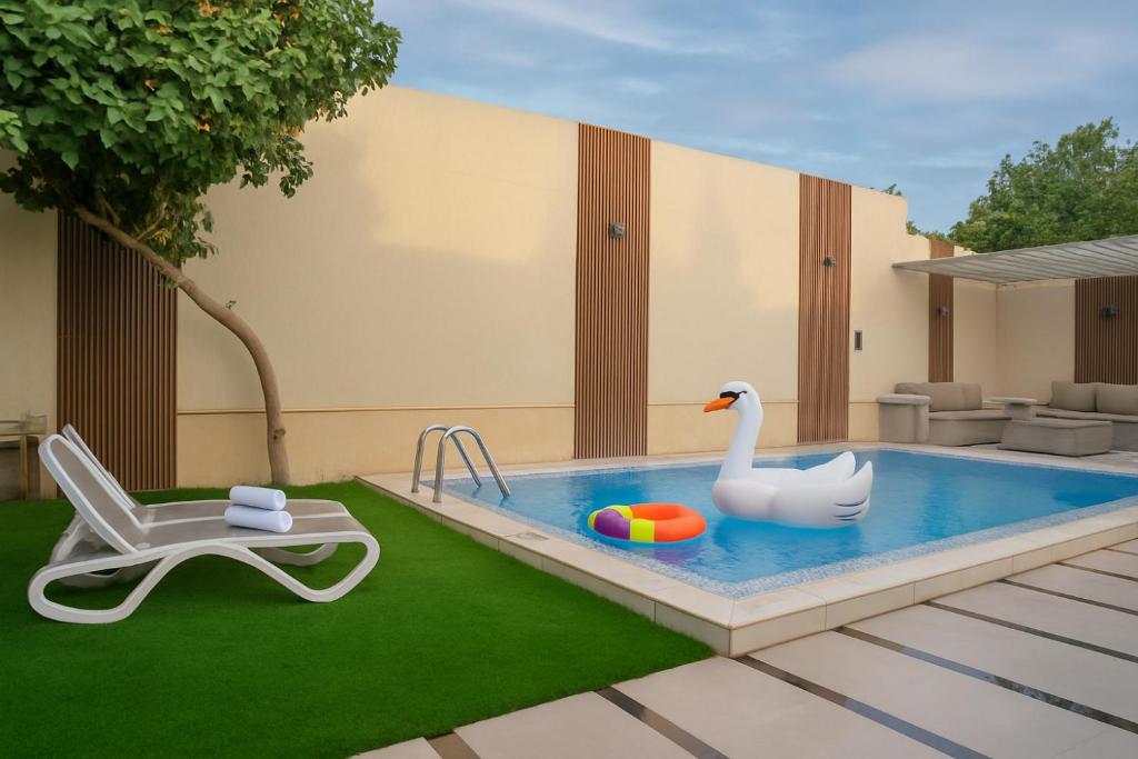 une piscine avec un cygne, une chaise et un jouet cygne dans l'établissement شاليهات ومنتجعات ارجان بارك, à Riyad