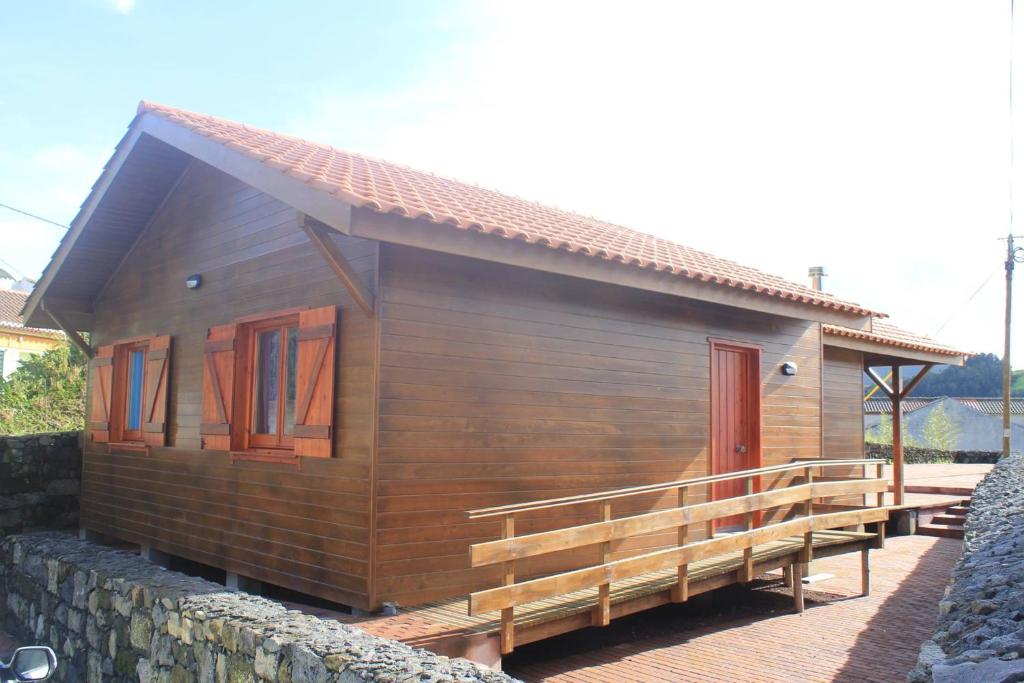 a small wooden house with a porch and a wall at Casa dos Manos in Furnas