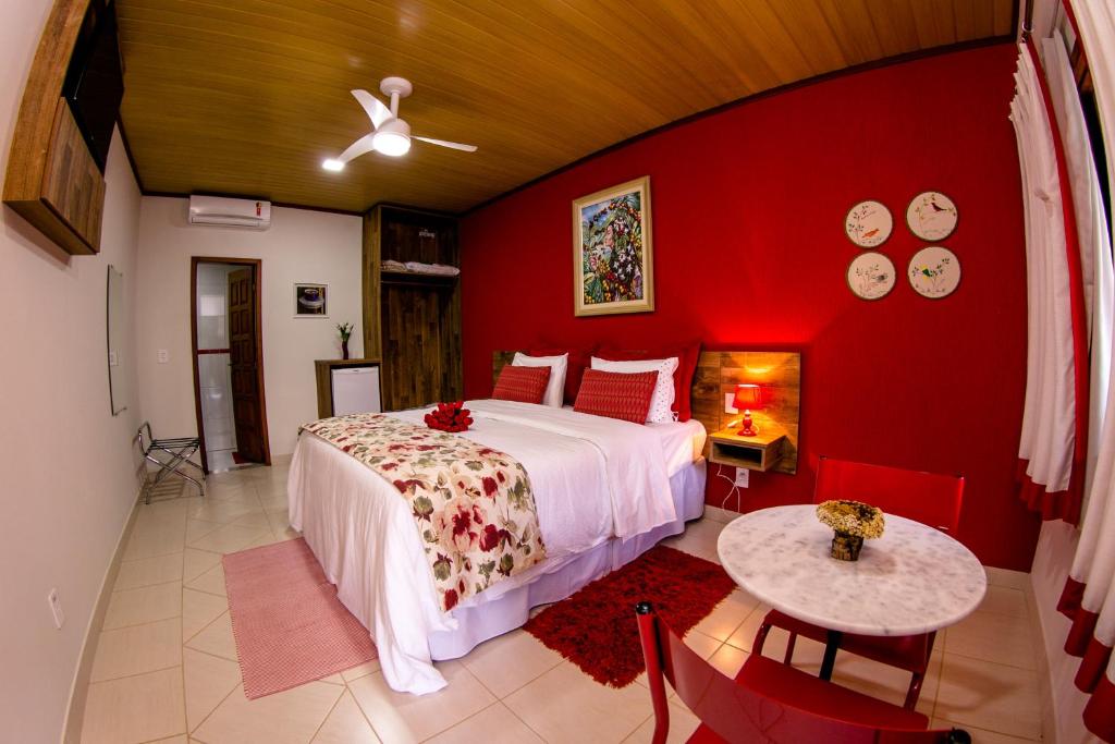 1 dormitorio con cama y pared roja en Chez Domaine Pousada Organica en Pedra Azul