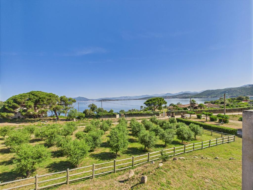 a garden with trees and water in the background at Résidence Aigue Marine in Coti-Chiavari