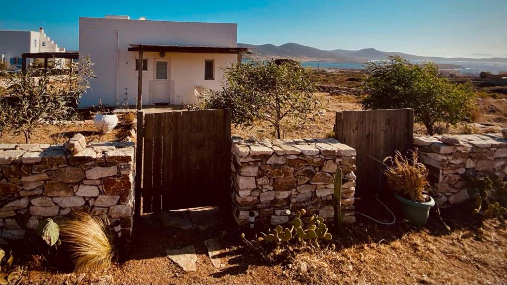 a stone fence and a building in a field at Antiparos Private House Agios Georgios in Antiparos