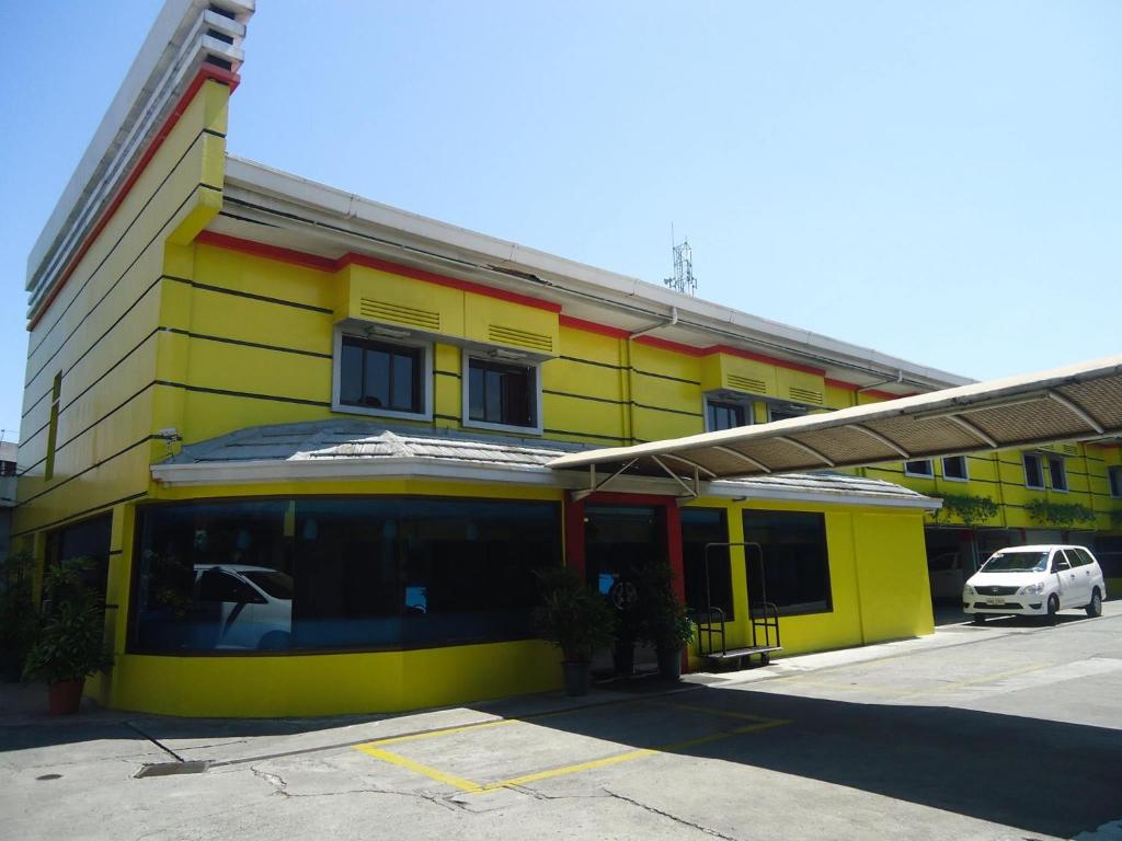 a yellow building with a car parked in front of it at Park Bed and Breakfast Hotel Pasay in Manila