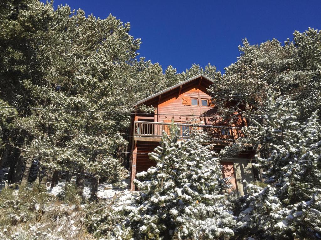 una cabaña de madera en el bosque con árboles nevados en Chalet Vue sous cet Angles, en Les Angles