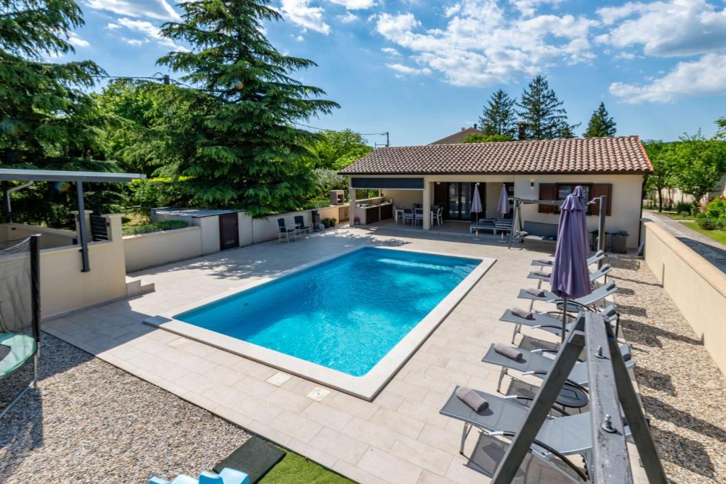 a swimming pool with chairs and a house at Villa Mediterranea, an idyllic new villa with a Mediterranean touch in Vinež