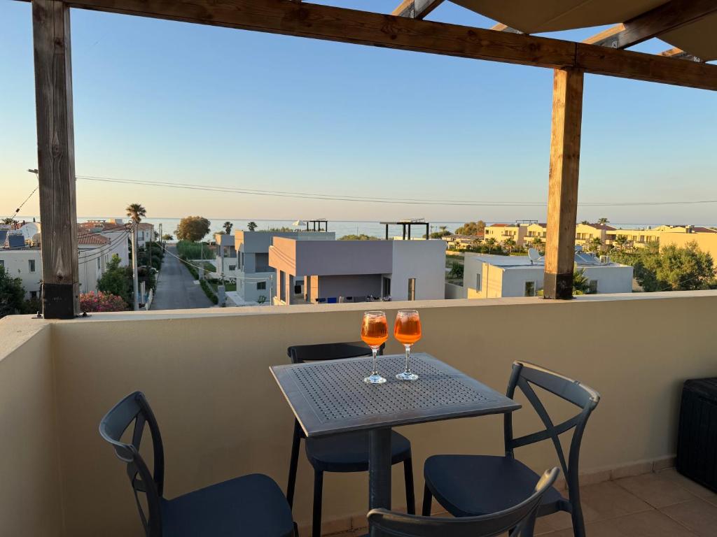 a table with two glasses of wine on a balcony at Cretan Odyssey Maisonette in Maleme